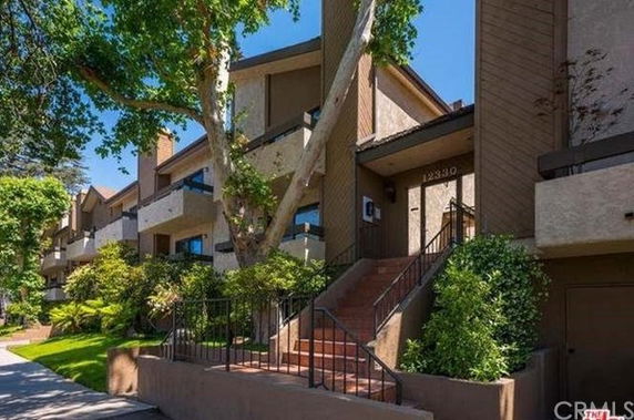 Front view of a multi-story residential building with stairs leading to the entrance.