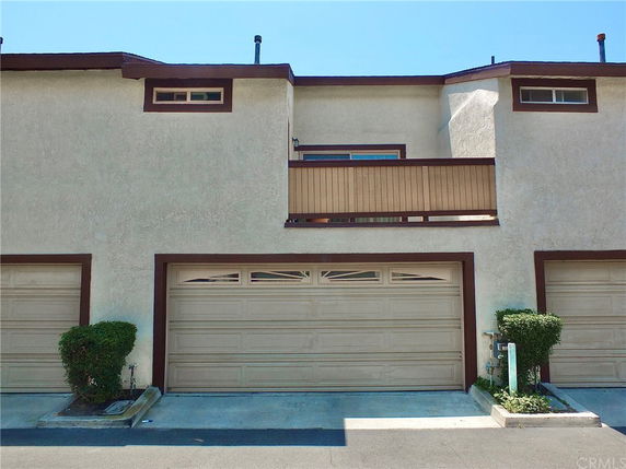 Front view of a two-story building with a garage and a small balcony.