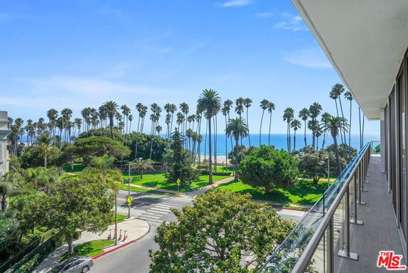 View of surrounding areas with palm trees and ocean from a building balcony.