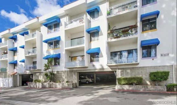 Front view of a multi-story residential building with blue awnings and balconies.