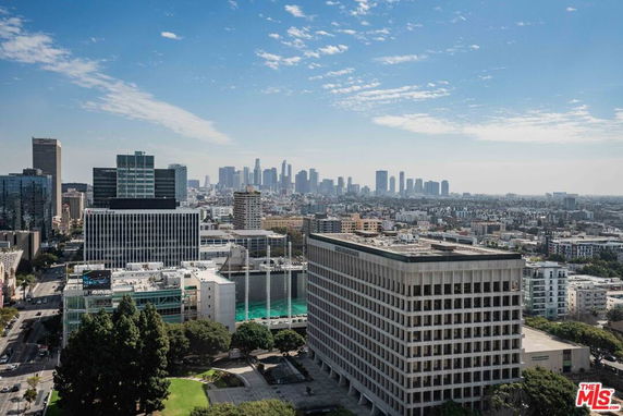 Aerial cityscape view with multiple modern buildings and a distant skyline.