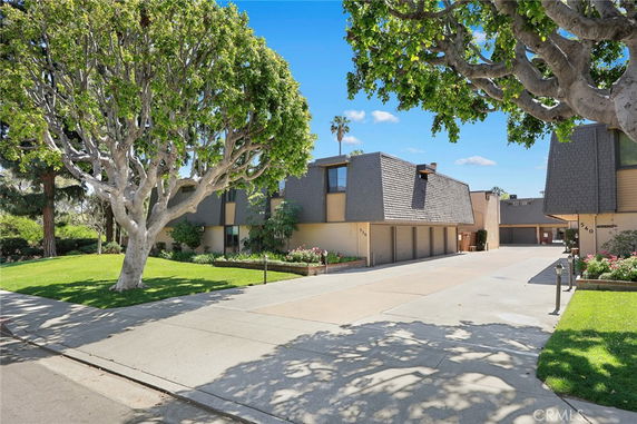 Front view of a modern multi-story building with distinctive roof design and garages.
