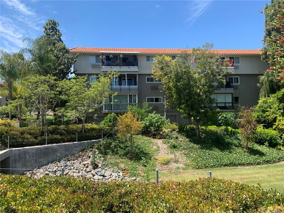 Front view of a multi-story residential building with balconies and a tile roof.