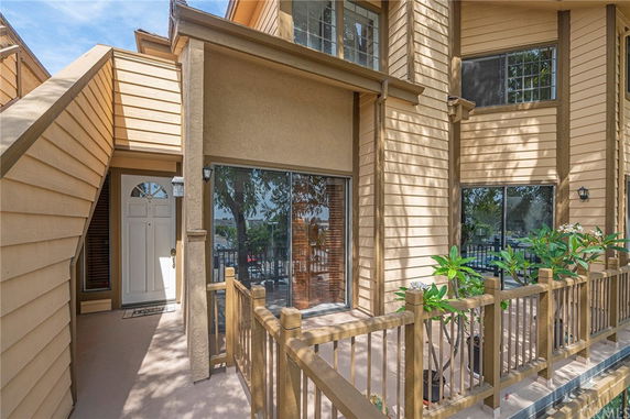 Front view of a multi-story house with wooden siding and balcony railing.