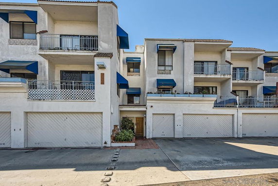 Front view of a multi-story residential building with balconies and garages.