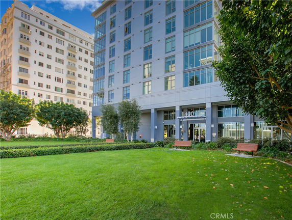 Front view of a multi-story building with large glass windows and landscaped entrance.
