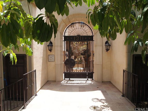 Entrance view of a building with an arched metal gate and surrounding foliage.