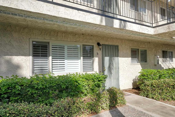 Front view of a residential building entrance with a metal door and windows with shutters.