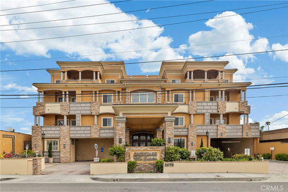 Front view of a multi-story building with balconies and a stone facade.