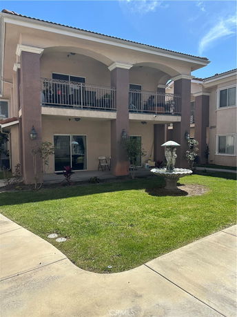 Front view of a two-story house with balconies and a fountain in the yard.