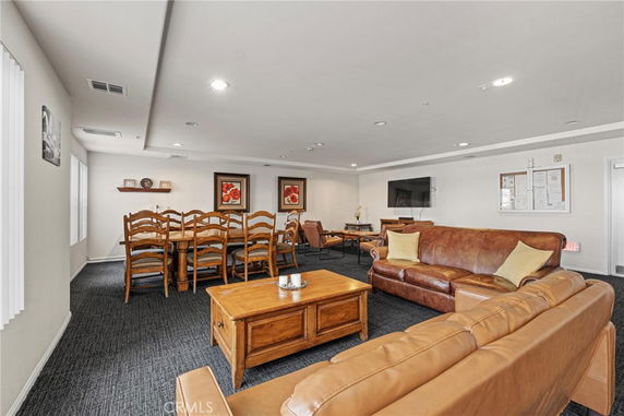 Interior of a clubhouse with sofas, a large dining table, and a mounted TV.