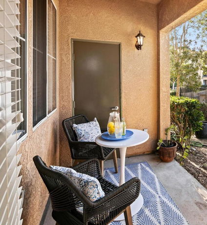 Outdoor patio area with two chairs, a small table, and a door leading inside.