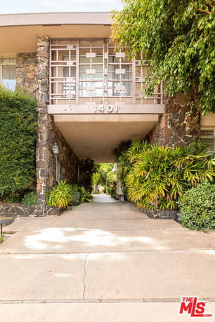 Front view of a building entrance with stone facade and greenery.