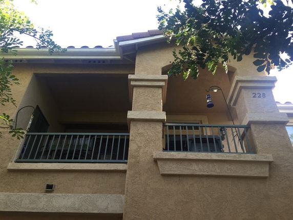 Front view of a two-story house with a balcony and stucco exterior.