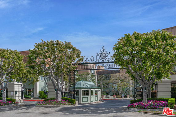 Entrance view of a gated residential complex with decorative iron gate and guardhouse.