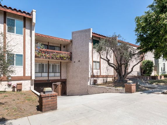 Front view of a multi-story building with balconies and a sloped driveway.