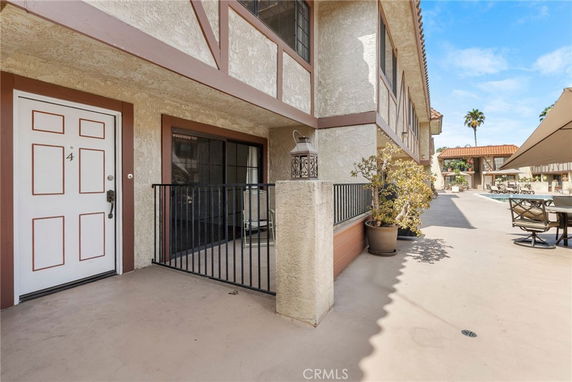 Front view of a house entrance with a small fenced patio area.