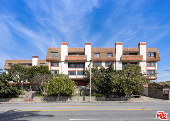Front view of a multi-story residential building with a unique roof design.