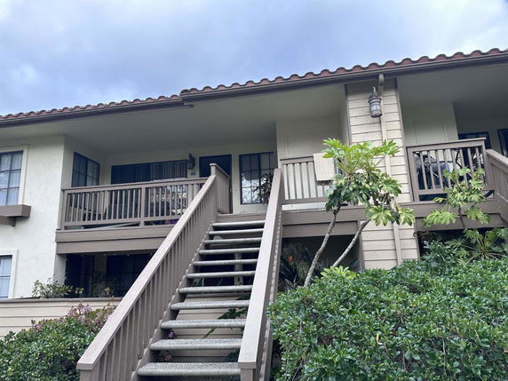 Front view of a two-story house with a staircase leading to the entrance and a balcony.