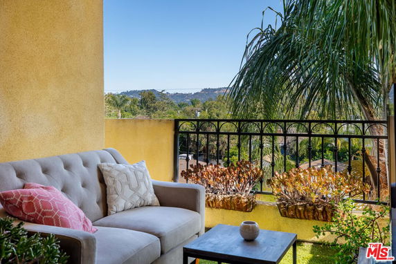 Balcony view overlooking a landscape with trees and hills in the distance.