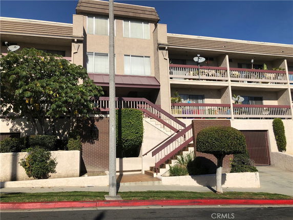 Front view of a multi-story residential building with external staircases and balconies.