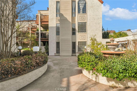 Front view of a multi-story residential building with balconies and a central pathway.