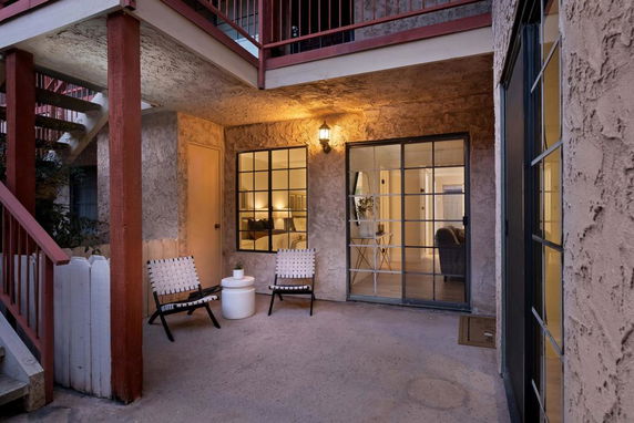 Front view of a two-story residential building with a balcony and patio area.