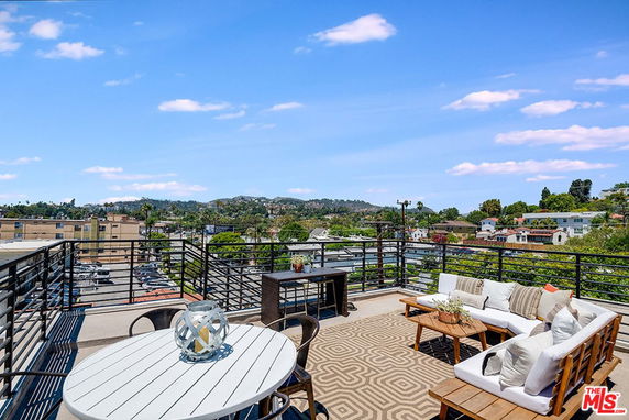 Rooftop area with seating and a view of surrounding cityscape and hills.