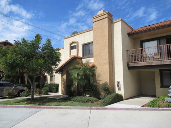 Front view of a two-story house with beige exterior and balcony.