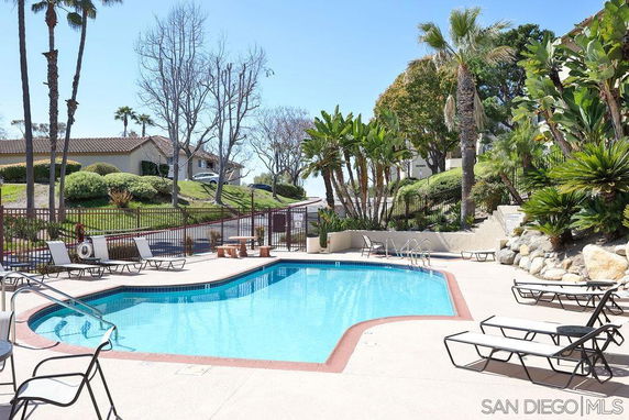 Outdoor swimming pool area with lounge chairs and surrounding greenery.