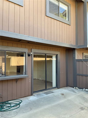 Exterior view of a two-story house with sliding glass door and windows.