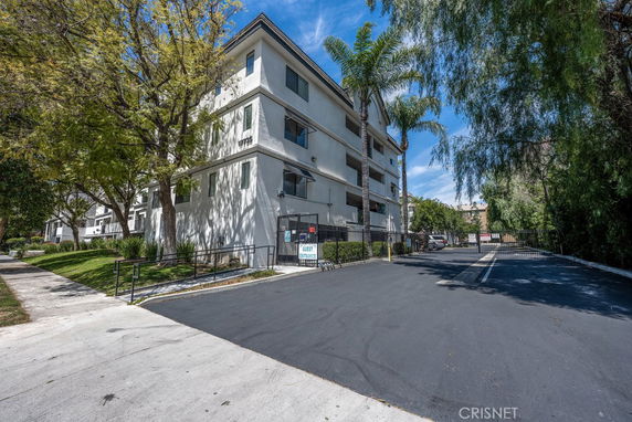 Front view of a multi-story residential building with a gated entrance.