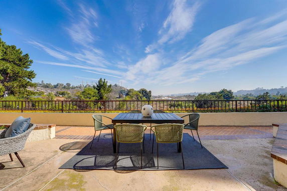 Outdoor patio with seating area and wide view of surrounding landscape and sky.