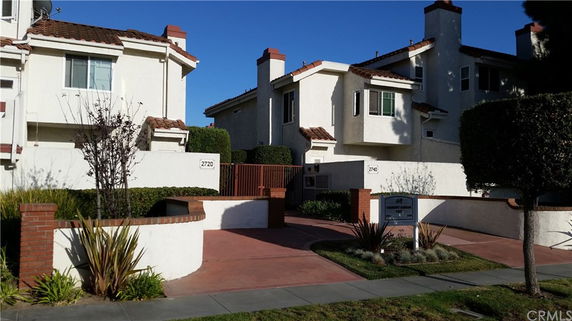 Front view of a multi-story residential building with white walls and red-tiled roofing.