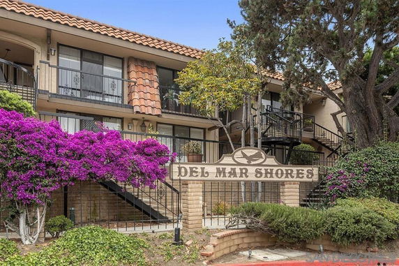 Front view of a multi-story building labeled Del Mar Shores with balconies and staircase.