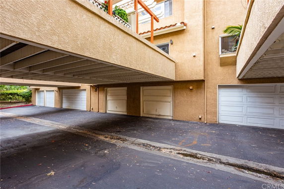 Outdoor parking area with multiple garages under a building.