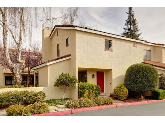 Front view of a two-story house with a red door and beige exterior.