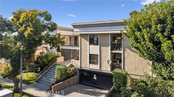 Front view of a multi-story apartment building with balconies and a gated entrance.