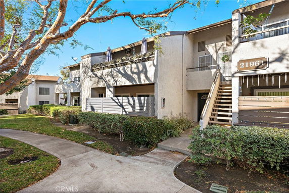 Front view of a two-story apartment building with balconies and entrance stairs.