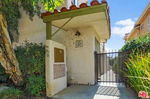 Entrance view of a building with a gated walkway and mailboxes.
