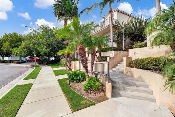 Front view of a two-story house with a balcony and landscaped entrance.