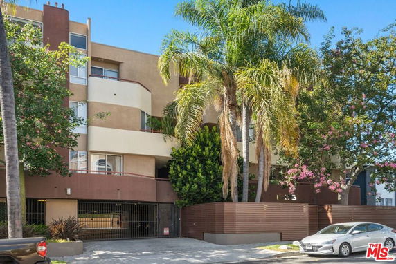 Front view of a multi-story residential building with balconies and a gated entrance.