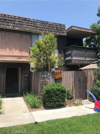 Front view of a two-story house with a balcony and wooden fence.