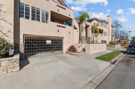 Front view of a multi-story residential building with a gated parking area.