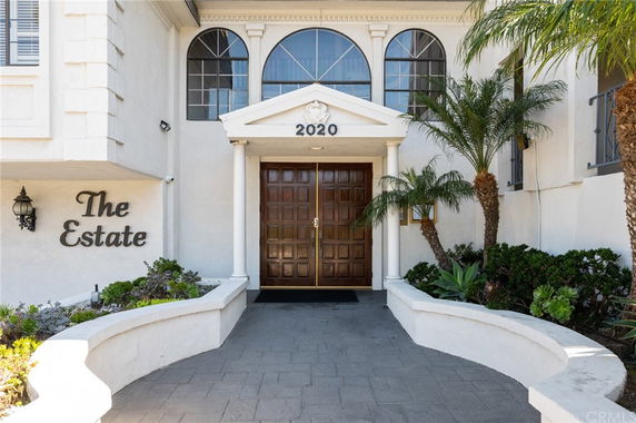 Front view of a building with a prominent entrance and decorative plants.