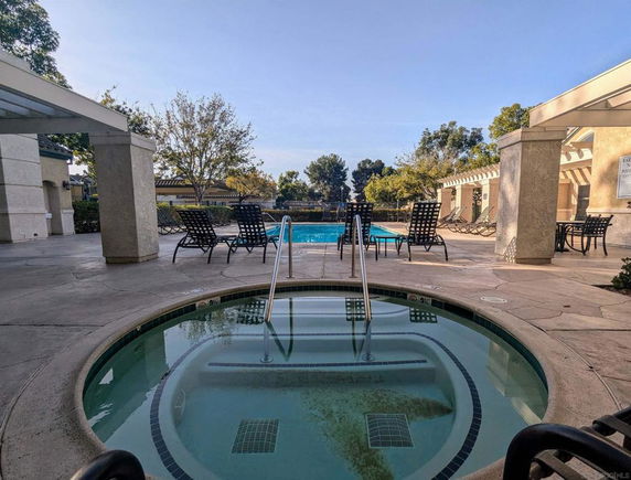 Outdoor view of a swimming pool and hot tub with surrounding lounge chairs.