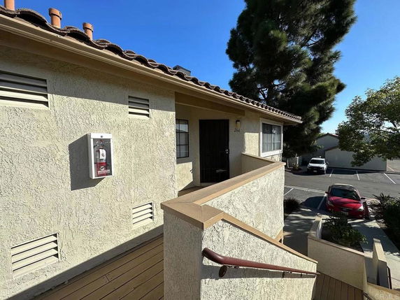 Exterior view of the upper level of a building with a staircase leading to an entry door.