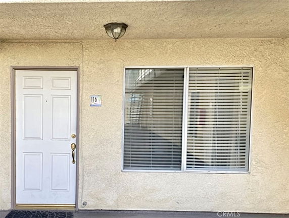 Front view of a building entrance with a closed door and a window with blinds.