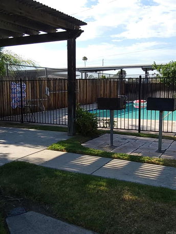 Outdoor swimming pool area with a fence and surrounding greenery.