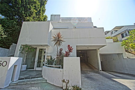 Front view of a modern multi-level house with a minimalist design and a driveway leading to the garage.